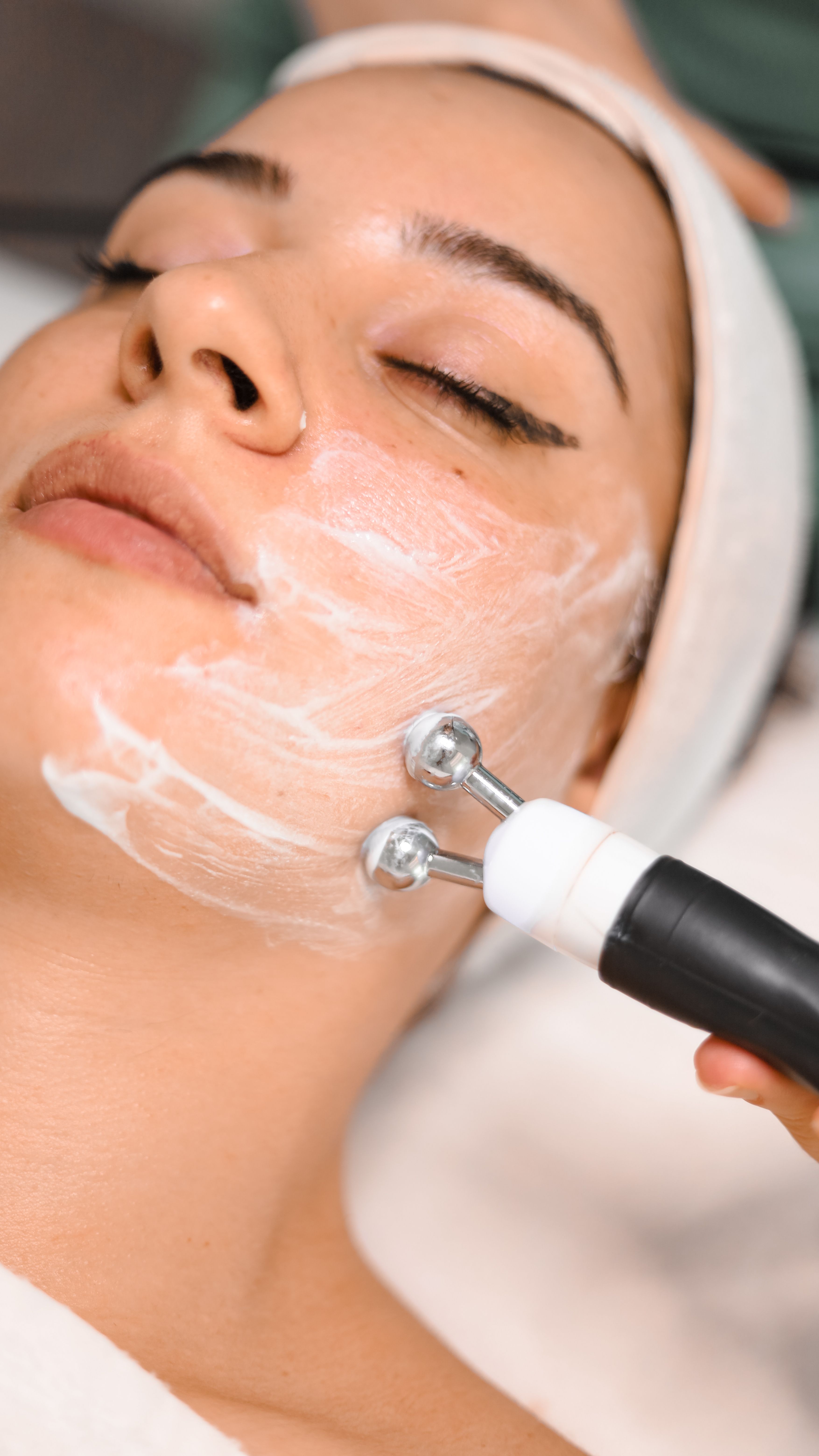 Close-up of a microchanneling device being used on a woman's cheek during a facial